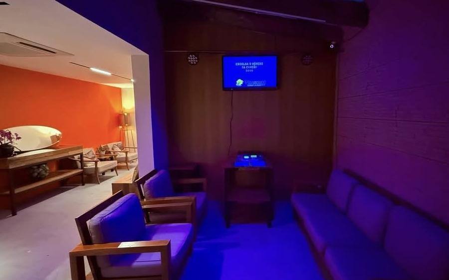 Sala de karaokê com sofás e telão