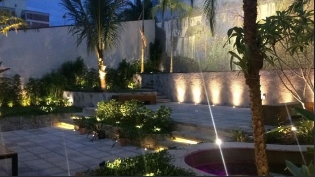 Jardim com iluminação e palmeiras ao anoitecer
